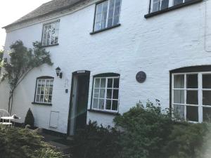 a white house with a green door and windows at Idyllic Stratford upon Avon cottage in Shottery