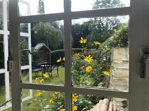 una ventana abierta con vistas a un jardín con flores amarillas en Idyllic Stratford upon Avon cottage en Shottery