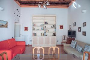 San Gregorio Luxury Apartments في نابولي: غرفة معيشة مع أرائك حمراء وتلفزيون