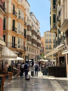 Un groupe de personnes marchant dans une rue avec des bâtiments dans l'établissement Acogedor apartamento en centro histórico Malaga, à Malaga