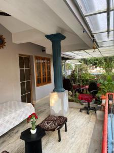 a porch with a fireplace and a bed and chairs at Homestay - Heaven Aumgarden in Trivandrum