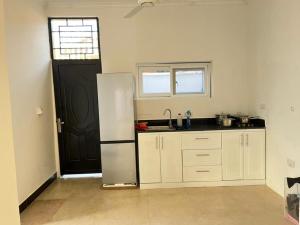 a kitchen with a refrigerator and a black door at Inviting 1-Bed Studio in Dar es Salaam in Dar es Salaam