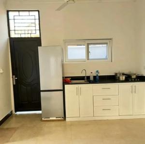 a kitchen with a white refrigerator and a black door at Inviting 1-Bed Studio in Dar es Salaam in Dar es Salaam