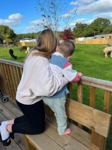 una mujer y un niño parados en una valla mirando animales en Jungle Book Safari Tent en Tenby