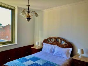 a bedroom with a bed and a window and a chandelier at Povoa Center Beach Apartment in Póvoa de Varzim