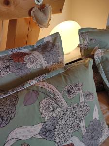 a bed with a blanket with a peacock design on it at Chambres d'hôtes Au Doubs Murmure in Les Fins