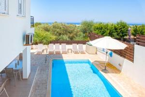 - une piscine avec un parasol à côté d'un bâtiment dans l'établissement Villa Ourania, à Protaras