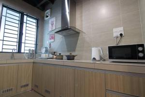 a kitchen with a counter with a microwave and a sink at Harmonia Homestay in Melaka