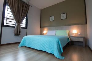 um quarto com uma cama azul e uma janela em Harmonia Homestay em Malaca