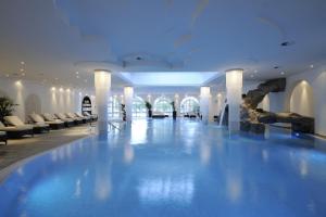 uma piscina no átrio do hotel com cadeiras brancas em Hotel Gut Ising em Chieming