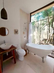 uma casa de banho com uma banheira, um WC e uma janela. em Saasil Kaax em Chemuyil