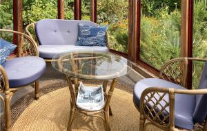 un porche cubierto con mesa de cristal y sillas en Awesome Home In Simrishamn With House Sea View, en Simrishamn