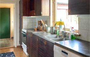 a kitchen with wooden cabinets and a sink and a window at Awesome Home In Simrishamn With House Sea View in Simrishamn