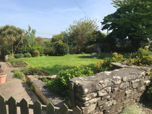 un jardín con una pared de piedra y un patio en Ancaire Studio, en Schull