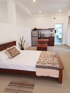 a bedroom with a large bed and a kitchen at Pearl's Homestay Matale in Matale