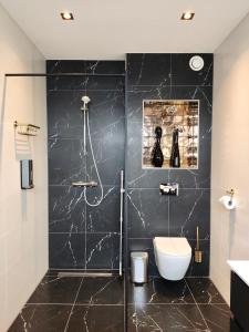 a black bathroom with a shower and a toilet at Bed & Breakfast Slaperduin in Buren