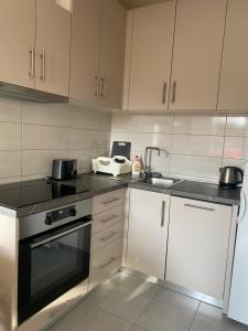 a kitchen with white cabinets and a black stove top oven at NaPjacu with own parking and garden in Herceg-Novi