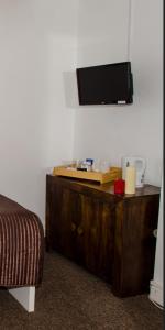 een kamer met een bed en een tv aan de muur bij Campbells Guest House in Leicester