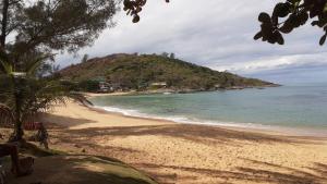 a sandy beach with a small island in the ocean at Apartamento com vista para o mar em Setiba Guarapari in Guarapari