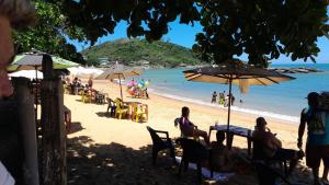 a beach with people sitting at tables and umbrellas at Apartamento com vista para o mar em Setiba Guarapari in Guarapari