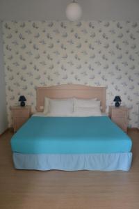 a bedroom with a blue bed with birds on the wall at Valente Perlia Rooms in Poros