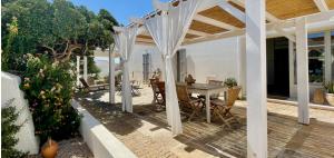 eine Terrasse mit einem Tisch und einer weißen Pergola in der Unterkunft Dimora Ferralasco in Carloforte