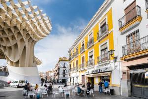 un grupo de personas sentadas en una calle con edificios en Anfitrión Sevilla 6, en Sevilla