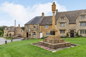 een stenen huis met een klokkentoren ervoor bij The Cotswold Lady in Guiting Power