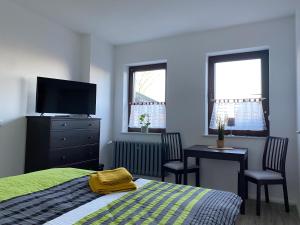 a bedroom with a bed and a tv and a table at Pension Kirschgarten in Nebra