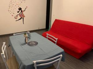 um quarto com uma mesa e um sofá vermelho em Chez Elo em Le Tréport
