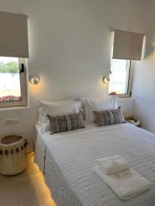 a white bedroom with a large white bed with pillows at Thealos Santorini ( close to square) in Pirgos