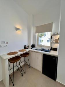 a kitchen with a sink and two bar stools at Thealos Santorini ( close to square) in Pyrgos