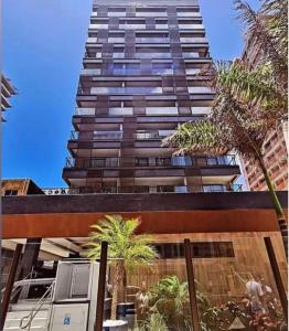 a tall building with palm trees in front of it at Apartamento luxuoso a poucos metros da praia in Salvador