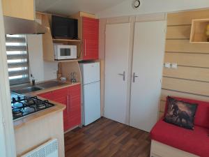 a small kitchen with red cabinets and a white refrigerator at La Muela in Cádiz