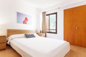 a white bedroom with a large bed and a window at Fantástico apartamento con WIFI in Port de Pollensa