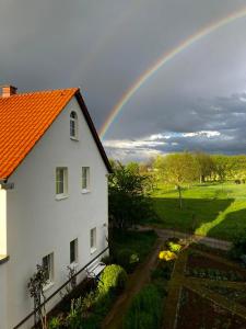 Roßwein的住宿－Ferienwohnung Zweinig02，一座带院子的白色房子上方的彩虹