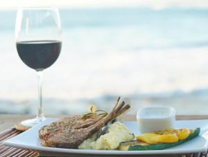 a plate of food with meat and a glass of wine at The Inn Manzanillo Bay in Troncones