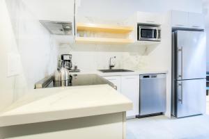 a kitchen with white counters and a refrigerator at Les Lofts St-Pierre - Par Les Lofts Vieux-Québec in Quebec City