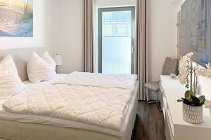 Schlafzimmer mit einem weißen Bett, einem Schreibtisch und einem Fenster in der Unterkunft Villa Deichgraf 12 "Meerblick" in Börgerende-Rethwisch