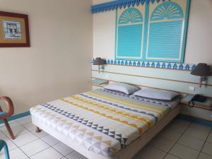 una camera da letto con un grande letto con una finestra blu di Studio CRISTAL COCO Martinique a Les Trois-Îlets