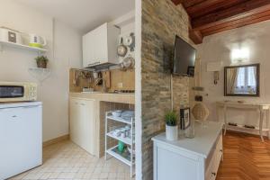 een keuken met witte kasten en een bakstenen muur bij Signoria Florentine Apartment in Florence