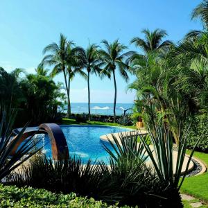 una piscina con palmeras y el océano en The Inn Manzanillo Bay, en Troncones