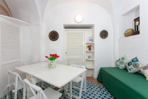 a white dining room with a white table and a green bed at Casa Colette in Anacapri