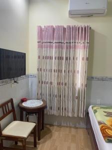 a room with a bed and a table and a curtain at Motel Hoa Hồng in Vung Tau