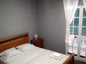 1 dormitorio con cama blanca y ventana en Casa MAR, en Madalena do Mar