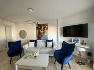uma sala de estar com um sofá branco e cadeiras azuis em Acapulco playa Nerja 407 planta superior em Nerja