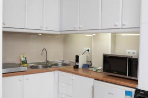 a kitchen with white cabinets and a sink and a microwave at Acapulco playa Nerja 407 planta superior in Nerja