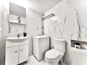 a white bathroom with a toilet and a sink at Odyseia Apts I at the center of the City & Old Town in Chania Town
