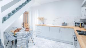 a kitchen with white cabinets and a table with chairs at The Hideout - free parking in Southampton