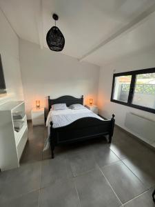 una camera con un letto nero e due finestre di Gujan-Mestras Chez Flo maison 4 places la hume a Gujan-Mestras